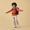 A young boy wearing a backpack stands with his arms outstretched against a plain background. Produktbild-Vorschau