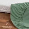 A green fitted sheet is draped over a mattress, with a wooden floor visible below. A thermometer icon and text indicating it's ideal for cold weather are present. Anteprima dell’immagine prodotto