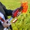 A person holding a toy blaster outdoors on a grassy field. Podgląd zdjęcia produktu