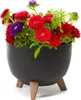 A black planter with wooden legs filled with colorful flowers. Náhled obrázku produktu