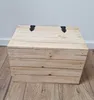 A wooden chest with black hinges sits on a wooden floor against a white and gray wall. Náhled obrázku produktu