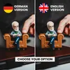 A split image showing two versions of a small figurine of a psychologist sitting in a chair, with flags and text indicating German and English versions. Produktbild-Vorschau