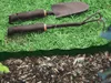 Gardening tools are placed on grass, with a border of mulch below. Produktbild-Vorschau