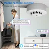 A woman is interacting with a smart home device, which is a smoke detector with temperature and humidity sensors, while a smart speaker is visible on a dresser. Podgląd zdjęcia produktu