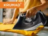 A person is ironing a yellow garment with a KRUMAD steam iron. Produktbild-Vorschau