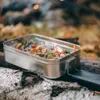 A metal lunchbox filled with food sits on a log in a forest setting. Voir les images du produit