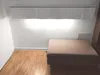 A room with a wall-mounted cabinet, a floor, and a large ottoman. Produktbild-Vorschau