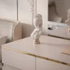 A close-up of a white bust figurine with a gold base placed on a light-colored dresser with gold trim. Produktbild-Vorschau