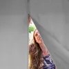 A woman peeking through the zipper of a gray tent or pavilion. Produktbild-Vorschau