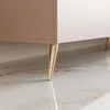 A close-up shot of the gold-colored metal legs of a TV stand, resting on a marble floor. Voir les images du produit