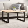 A coffee table with a wooden top and black metal legs is placed in front of a sofa with cushions. Podgląd zdjęcia produktu