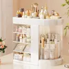 A white rotating makeup organizer filled with various cosmetic products, displayed on a light pink background. Náhled obrázku produktu
