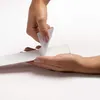 Hands peeling backing off a white strip. Voir les images du produit