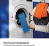 A hand holding a blue cleaning pad in front of a washing machine with an orange cloth inside. Anteprima dell’immagine prodotto
