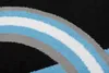 A close-up view of a rug with a curved pattern of black, gray, light blue, and white stripes. Voir les images du produit