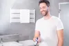 A man in a bathroom holding a hair clipper. Produktbild-Vorschau