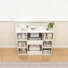 A white bookshelf filled with books and decorative items, placed against a window with blinds. Podgląd zdjęcia produktu