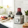 A KitchenAid blender with a smoothie in the blending cup, surrounded by berries, bread, and decorative jars on a kitchen counter. Voir les images du produit