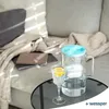 A glass water pitcher and a glass of water with lemon are on a table next to a sofa. Náhled obrázku produktu