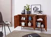 A wooden sideboard with decorative elements and various items displayed on and inside it, set in a room with a chair and rug. Náhled obrázku produktu