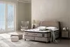 A bedroom scene featuring a bed, armchair, and ottomans. Produktbild-Vorschau