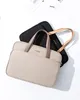 Two laptop bags are shown, one beige and one black, on a white background with some papers in the upper left corner. Anteprima dell’immagine prodotto
