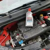 A bottle of NIGRIN KFZ-Kühler-Frostschutz Universal is placed on top of a car engine. Produktbild-Vorschau