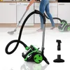 A person vacuums a kitchen floor, with a vacuum cleaner and its accessories shown prominently in the foreground.