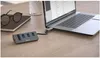 A USB hub and card reader connected to a laptop on a wooden desk, with glasses and a notebook nearby. Anteprima dell’immagine prodotto