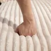 A hand presses into a soft, beige, ribbed fabric. Náhled obrázku produktu