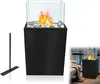 A black freestanding ethanol fireplace with a glass enclosure and burning flames, shown with a separate metal stand. Náhled obrázku produktu
