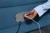 A person's hand is plugging a USB cable into a port on an air mattress. Produktbild-Vorschau