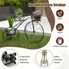 A black metal bicycle-shaped plant stand with three baskets holding plants, placed on a grassy lawn. Anteprima dell’immagine prodotto