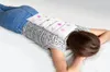 A person lying on their stomach with a heat pack on their lower back. Produktbild-Vorschau