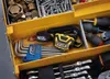 A close-up view of a yellow toolbox filled with various tools and hardware. Produktbild-Vorschau