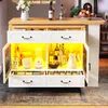 A white bar table with a wooden top, featuring drawers and cabinets with yellow LED lighting. It is stocked with various items like bottles, bowls, and kitchen appliances. Anteprima dell’immagine prodotto
