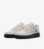 A pair of Nike Air Force 1 '07 sneakers with a gray upper and black sole, presented against a white background. Produktbild-Vorschau
