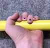 A hand holding a yellow bar, with painted designs on the fingernails. Voir les images du produit