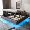 A bed with its storage compartment open, revealing folded linens and clothing, illuminated by blue LED lights underneath. Náhľad obrázku produktu