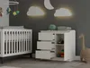 A nursery room with a crib, a dresser, and decorative elements.