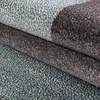 A close-up view of a folded carpet with an abstract pattern. Podgląd zdjęcia produktu