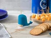 A blue whale-shaped toothpick dispenser is shown on a wooden table with crackers and cheese cubes on toothpicks in the background. Náhled obrázku produktu