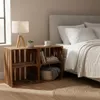 A bedroom scene with a bed, nightstand made of wooden crates, and a lamp. Produktbild-Vorschau