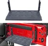 A product shot of a folding metal table designed to attach to the tailgate of a Jeep Wrangler JK, shown both in isolation and mounted on a vehicle's tailgate. Náhled obrázku produktu