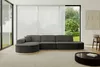 A modern living room with a large sectional sofa, large windows with sheer curtains, and a coffee table.