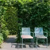 Two outdoor chairs with cushions are placed on a patio surrounded by lush greenery. Anteprima dell’immagine prodotto