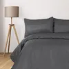 A close-up view of a bed with anthracite-colored bedding and a floor lamp. Produktbild-Vorschau