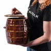 A person is holding a brown ceramic fermentation pot with a lid. Podgląd zdjęcia produktu