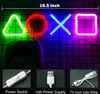 A neon sign shaped like PlayStation controller buttons, a controller, and accessories are displayed against a dark, grid-like background. Produktbild-Vorschau