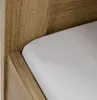 A close-up view of a wooden bed frame with a white mattress. Produktbild-Vorschau